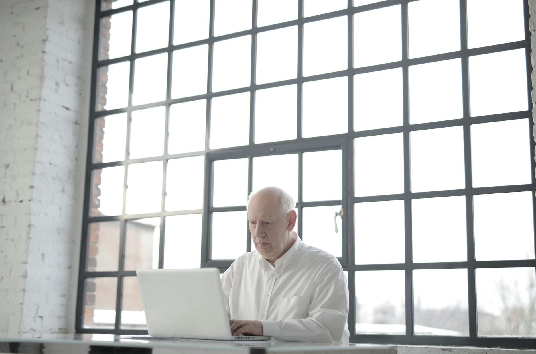 Focused person working on laptop in bright modern office, verifying whether job postings are real
